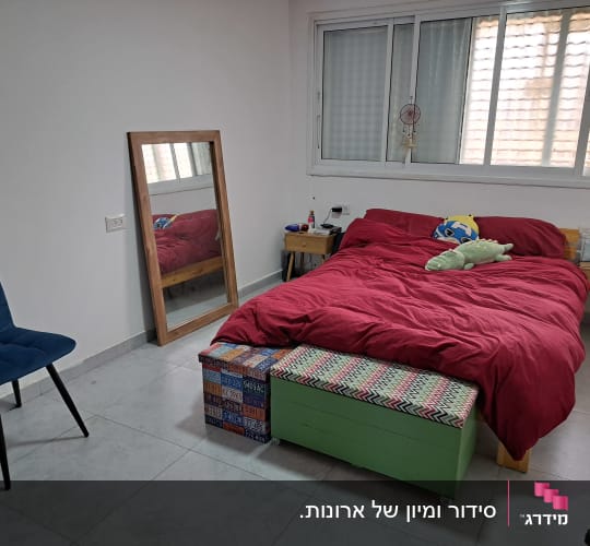 חדר שינה מסודר עם מיטה, כיסא ומראה
